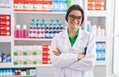 Young hispanic woman pharmacist smiling confident standing with arms crossed gesture at pharmacy
